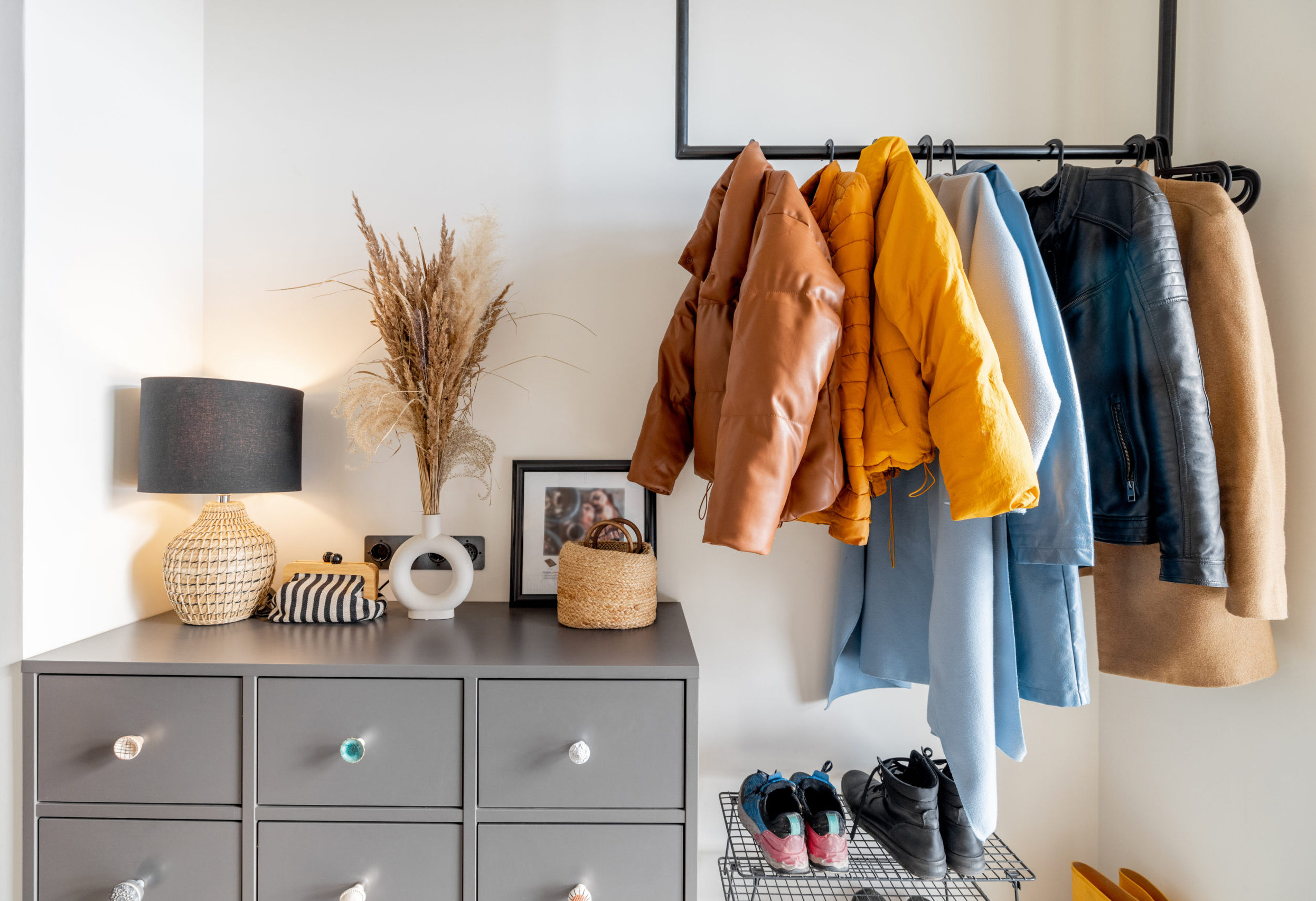 Heller Hausflur mit weißer Kommode, Schuhregal und Kleidung auf Kleiderbügeln – ordentliche und aufgeräumte Einrichtung